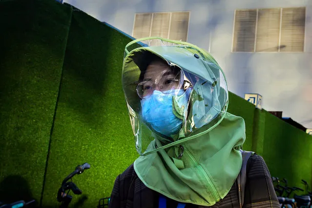 A woman wearing a facemask and a design clothing face shield amid the concerns over the COVID-19 coronavirus walks on a street in Beijing on April 20, 2020. China's economy shrank for the first time in decades last quarter as the coronavirus paralysed the country, in a historic blow to the Communist Party's pledge of continued prosperity in return for unquestioned political power. (Photo by Nicolas Asfouri/AFP Photo)