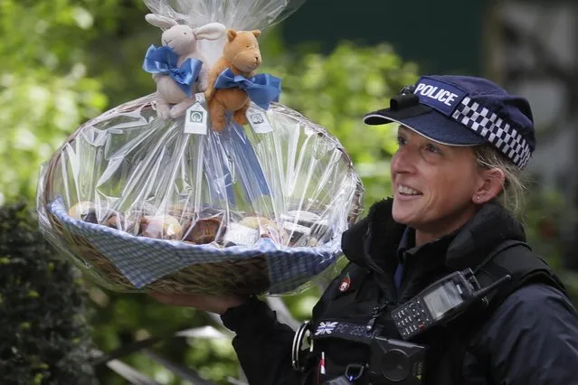 A police officer carries a gift basket for Prime Minister Boris Johnson and his partner Carrie Symonds sent on occasion of the birth of their son into No. 10 Downing Street in London, Britain, 01 May 2020. The United Kingdom's 66 million inhabitants are living through their sixth consecutive week of nationwide lockdown prompted by the ongoing pandemic of the COVID-19 disease caused by the SARS-CoV-2 coronavirus. (Photo by Kirsty Wigglesworth/AP Photo)