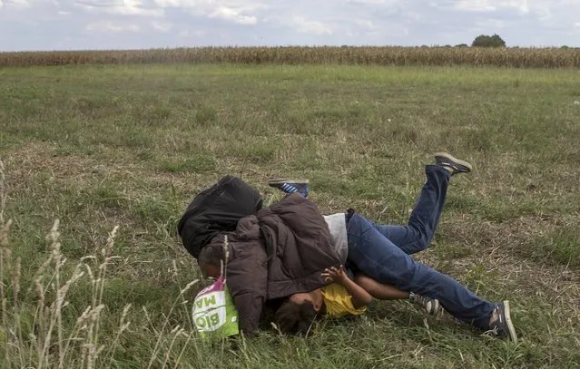 A migrant falls over a child as he tries to escape from a collection point in Roszke village, Hungary, September 8, 2015. (Photo by Marko Djurica/Reuters)