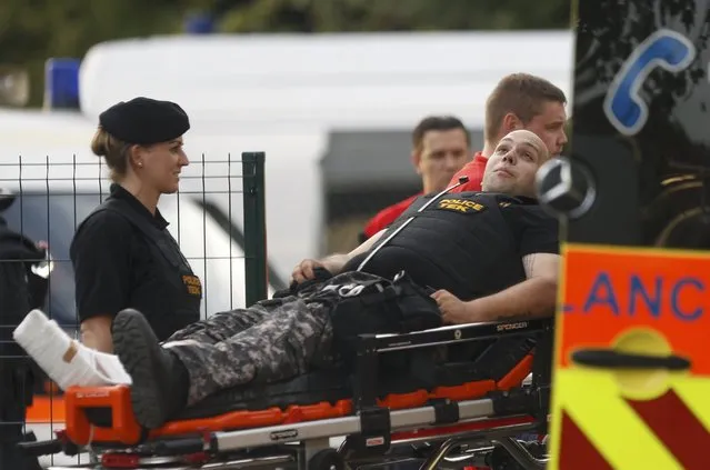 An injured Hungarian riot policeman is taken to an ambulance in Roszke, Hungary September 16, 2015. (Photo by Dado Ruvic/Reuters)