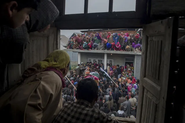In this November 14, 2017, file photo, Kashmiri villagers watch from a window of a residential house as people carry the body of Ashiq Ahmed Bhat, a local rebel during his funeral in Palhalan, some 35 kilometers (22 miles) north of Srinagar, Indian controlled Kashmir. A pair of gunbattles have left three rebels and an Indian army soldier dead in the disputed Himalayan region of Kashmir, police said on Tuesday. (Photo by Dar Yasin/AP Photo)