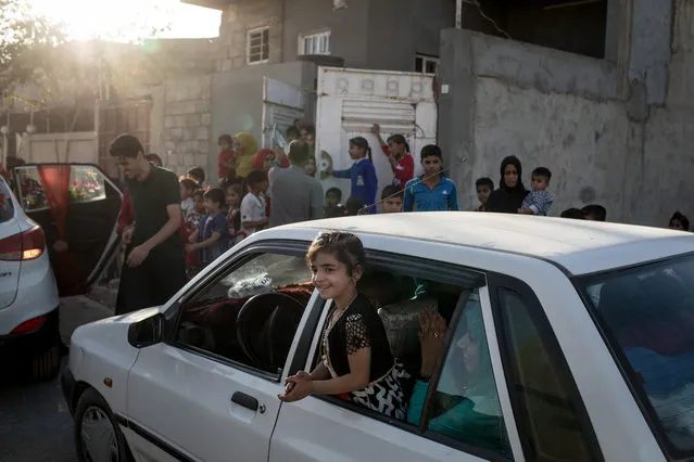 A young girl claps and sings from a car window while celebrating a wedding in West Mosul on November 3, 2017 in Mosul, Iraq. (Photo by Chris McGrath/Getty Images)