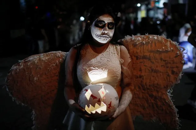 A reveller dressed as an angel participates in a parade known as “La Calabiuza” on the eve of the Day of the Dead in Tonacatepeque, El Salvador on November 1, 2022. (Photo by Jose Cabezas/Reuters)