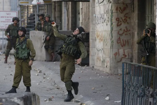 An Israeli army soldier throws a sound grenade at Palestinians during clashes following the funeral of 19-year-old Palestinian student Hadeel al-Hashlamun in the occupied West Bank city of Hebron September 23, 2015. (Photo by Mussa Qawasma/Reuters)