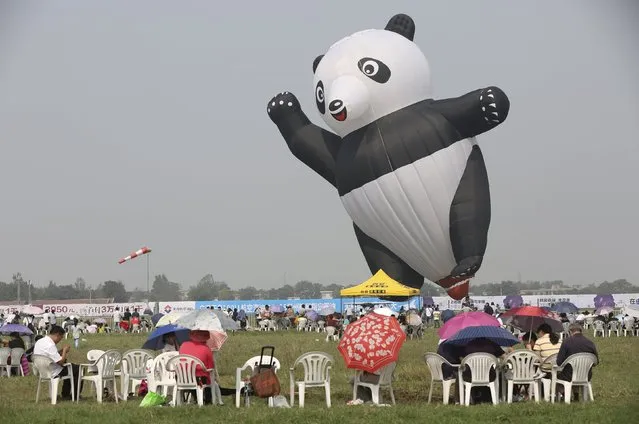 A giant balloon in the shape of a panda is seen as spectators gather to watch the performances at an air show in Zhengzhou, Henan province, China, September 25, 2015. (Photo by Reuters/Stringer)