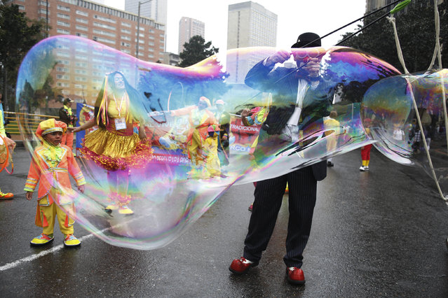 A clown creates a huge bubble during an anti-government protest in Bogota, Colombia, Tuesday, May, 9, 2017. Members of the National Union of Circus Artists from across the country marched in Bogota to protest the government's economic policies, demand better job opportunities and better access to healthcare. (Photo by Fernando Vergara/AP Photo)