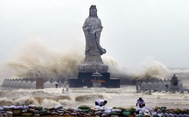 People set up sand bags to reinforce an embankment in front of an Avalokitesvara Bodhisattva statue as waves brought by Typhoon Dujuan slam the coastline in Quanzhou, Fujian province September 29, 2015. China ordered tens of thousands of boats back to shore and closed tourist attractions as a typhoon made landfall in the eastern province of Fujian early on Tuesday after leaving two dead and hundreds injured in Taiwan. (Photo by Reuters/China Daily)