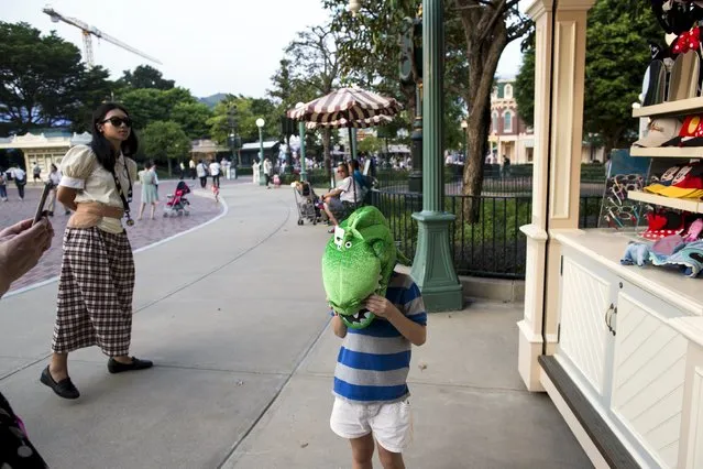 A child wears a head mask as his mother takes a photo, before the 10th anniversary ceremony of Hong Kong Disneyland in Hong Kong, China September 11, 2015. (Photo by Tyrone Siu/Reuters)