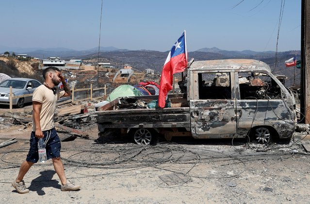 A volunteer walks next a burned truck following the spread of wildfires in Quilpue, Chile on February 6, 2024. (Photo by Rodrigo Garrido/Reuters)