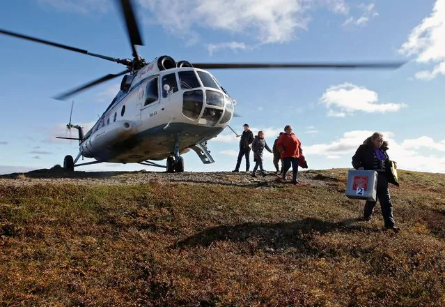Members of a local electoral commission walk near an Mi-8 helicopter during early voting in the elections to the lower house of parliament in remote areas at a reindeer camping ground on the banks of the Barents Sea, north of Naryan-Mar in Nenets region, Russia September 12, 2016. (Photo by Sergei Karpukhin/Reuters)