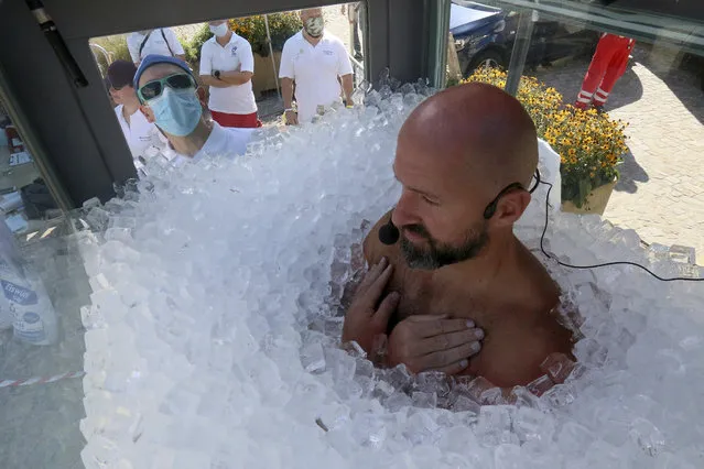 Austrian ice swimmer Josef Koeberl is standing in a glass cabin filled with ice try to break the world record for a human to stay side an ice box in Melk, Saturday, September 5, 2020. (Photo by Ronald Zak/AP Photo)