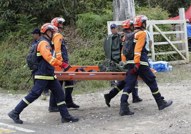 Rescue team prepare equipment near the site of a landslide at an organic farm in Batang Kali, Malaysia, Friday, December 16, 2022. Dozens of Malaysians were believed to have been at a tourist campground in Batang Kali, outside the capital of Kuala Lumpur, when the incident occurred, said a district police chief. (Photo by F.L. Wong/AP Photo)