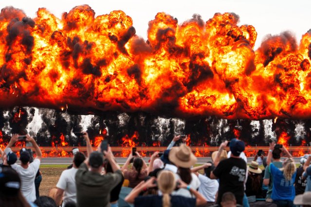 Spectators look on as a wall of fire is ignited on March 28, 2025 in Avalon, Australia. The Avalon Australian International Airshow 2025, scheduled from March 25-30 at Avalon Airport in Victoria, is set to be the largest aviation event in the Southern Hemisphere, featuring both industry trade days and a public airshow. The event will showcase a wide range of aircraft, from historic warbirds to cutting-edge military jets, along with over 700 exhibitors from the aerospace, aviation, and defence sectors, offering visitors a unique opportunity to experience the latest in global aviation technology and thrilling aerial displays. (Photo by Asanka Ratnayake/Getty Images)