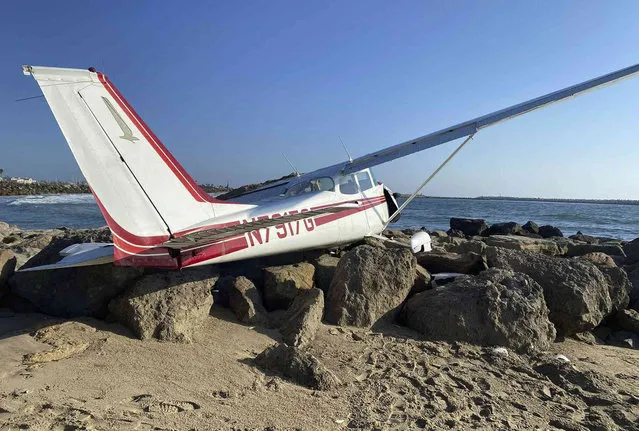 In a photo provided by the Ventura Police Department, a plane lies on the jetty at the beach at Marina Park after a crash Friday, September 16, 2022, in Ventura., Calif. The three occupants escaped unharmed, authorities said. (Photo by Ventura Police Department via AP Photo)
