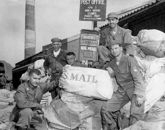 Capt. Leo Roesser (left), of Rochester, New York and his crew of four pose with mail bags full of welcome news from home for U.S. 7th Division GI's somewhere in Korea on October 15, 1950. Note the fancy stateside mailbox in background, the only in Korea, which was never designed for this volume of postal business. GI's left to right are: Cpl. Robert Freeberg, Colfax, Wis.; Cpl. Alpehns Davis, Wake Forrest, N.C.; Lt. Edward M. Weinbaum, Portland, Ore.; and Sgt. Gerald Drolet, Lowell, Mass. (Photo by AP Photo)