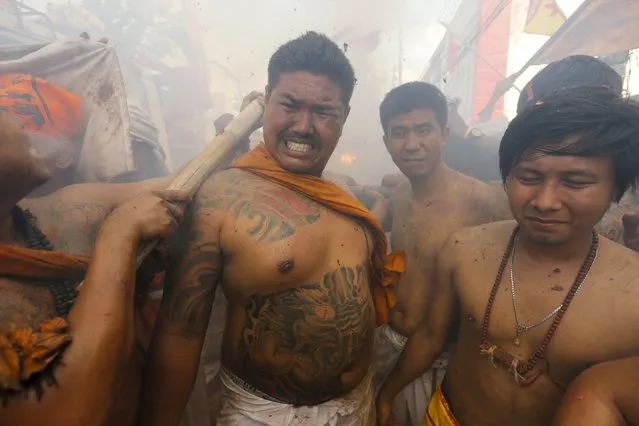 Devotees of the Chinese Ban Tha Rue shrine reacts as fire crackers explode during a procession celebrating the annual vegetarian festival in Phuket, Thailand, October 17, 2015. The festival, featuring face-piercing, spirit mediums and strict vegetarianism celebrates the local Chinese community's belief that abstinence from meat and various stimulants during the ninth lunar month of the Chinese calendar will help them obtain good health and peace of mind. (Photo by Jorge Silva/Reuters)