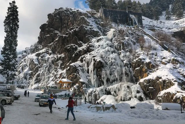 Kashmiri locals and tourists walk near a frozen waterfall in the Drang area of Tangmarg, north of Srinagar, the summer capital of Indian Kashmir, 16 January 2023. Tourist Station and waterfall at Drang area of Tangmarg is frozen due to a fall in temperature. Ski resort Gulmarg recorded a low of minus 12.0°C and It was the coldest night so far recorded in the region. (Photo by Farooq Khan/EPA/EFE)