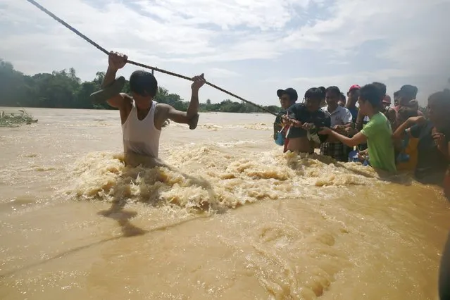 Residents hold on a rope to board a truck while crossing floodwaters brought by typhoon Koppu that battered Candaba town, Pampanga province, north of Manila October 20, 2015. (Photo by Romeo Ranoco/Reuters)