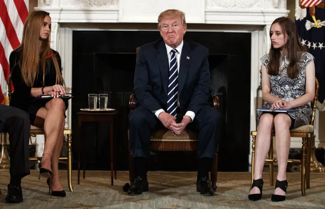 President Donald Trump, joined by Marjory Stoneman Douglas High School student Carson Abt, right, and Julia Cordover, the student body president at the school, pauses during a listening session with high school students teachers and others in the State Dining Room of the White House in Washington, Wednesday, February 21, 2018. (Photo by Carolyn Kaster/AP Photo)