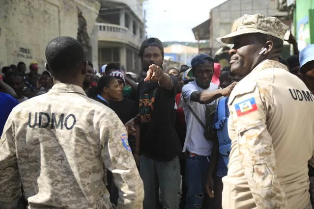 Police officers block a group of persons as they protest against the arrival of the USNS Comfort hospital ship in Jeremie, Haiti, Tuesday, December 13, 2022. (Photo by Joseph Odelyn/AP Photo)