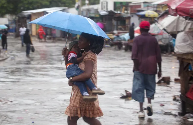 A woman carrying a child walks in the rain triggered by Hurricane Matthew in Port-au-Prince, Haiti, Tuesday, October 4, 2016. (Photo by Dieu Nalio Chery/AP Photo)