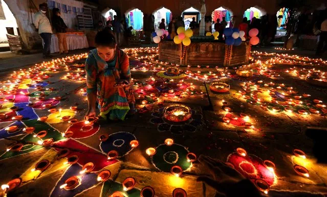 An Indian young woman lights an oil lamp during the Deep Utsav, or Light Festival, at the historical Gauhar Mahal palace, as part of the Diwali festival celebrations in Bhopal, India, 09 November 2020. The Diwali festival of lights symbolizes the victory of good over evil, commemorating Lord Ram's return to his kingdom Ayodhya after completing a 14-year exile. Diwali will be celebrated on 14 November 2020. (Photo by Sanjeev Gupta/EPA/EFE)