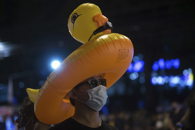 A protester wears an inflatable yellow duck, which has become a good-humored symbol of resistance during anti-government rallies, outside the headquarters of the Siam Commercial Bank, a publicly-held company in which the Thai King is the biggest shareholder, Wednesday, November 25, 2020, in Bangkok Thailand. (Photo by Wason Wanichakorn/AP Photo)