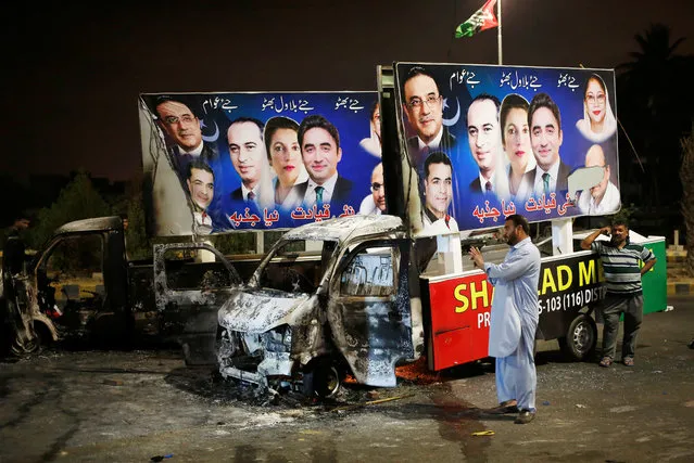 A man takes photographs of a wreckage of trucks carrying signs after the vehicles were, according to local media, set ablazed by an angry mob when political workers belonging to the Pakistan Peoples Party (PPP) and Imran Khan's Pakistan Tehreek-e-Insaf (PTI) clashed with each other in Karachi, Pakistan on May 07, 2018. (Photo by Akhtar Soomro/Reuters)