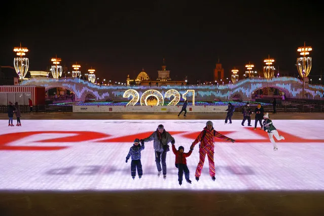 People skate during the opening of a skating rink at VDNKh (The Exhibition of Achievements of National Economy), in Moscow, Russia, Friday, November 27, 2020. The area of artificial ice cover is more than 20,000 sq. meters. (Photo by Alexander Zemlianichenko/AP Photo)