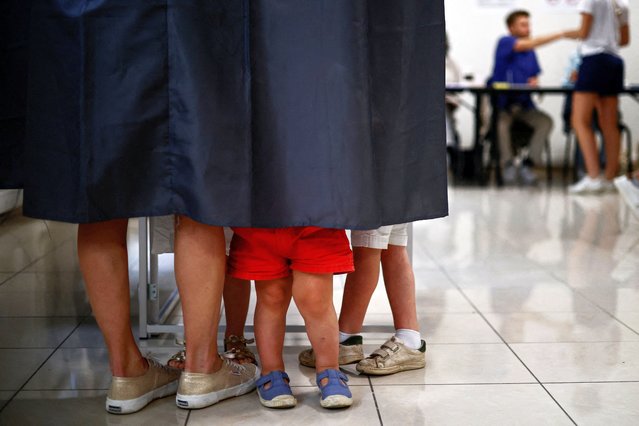 A woman and her children stand in a voting booth to vote in the second round of the early French parliamentary elections, at a polling station in Paris, France, on July 7, 2024. (Photo by Yara Nardi/Reuters)