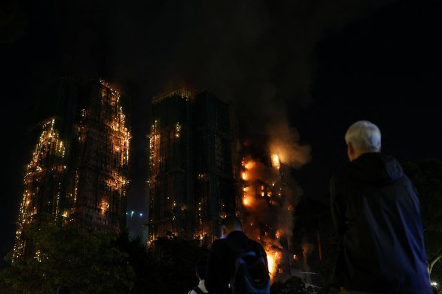 People watch as flames burn bamboo scaffolding across multiple buildings at Wang Fuk Court housing estate, in Tai Po, Hong Kong, China, on November 26, 2025. (Photo by Tyrone Siu/Reuters)