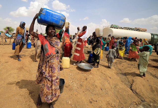 A Sudanese refugee woman, who fled the violence in Sudan's Darfur region, carries a jerrycan of water as she walks to her makeshift shelter near the border between Sudan and Chad in Koufroun, Chad on May 10, 2023. (Photo by Zohra Bensemra/Reuters)
