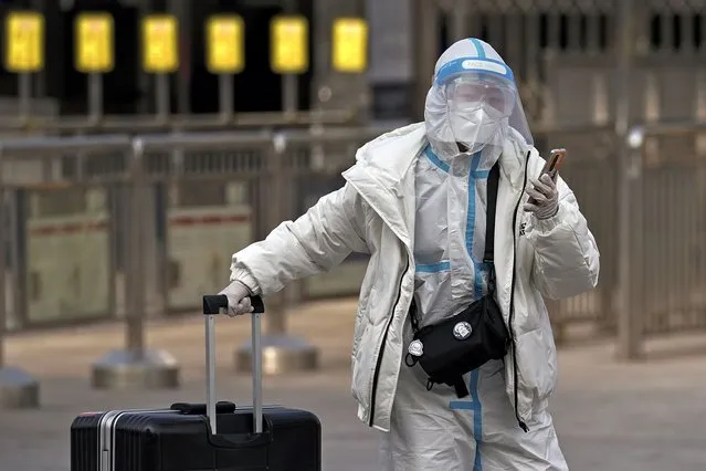 A woman wearing a protective gear to help curb the spread of the coronavirus walks with her luggage arrives to the railway station to catch her train in Beijing, Wednesday, January 27, 2021. China has given more than 22 million COVID vaccine shots to date as it carries out a drive ahead of next month's Lunar New Year holiday, health authorities said Wednesday. (Photo by Andy Wong/AP Photo)