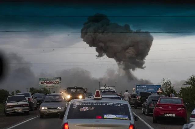 In this photo taken late Tuesday, June 18, 2013 a traffic jam forms on a highway blocked because of a fire at a military depot near Chapaevsk in the Samara region of southern Russia. Exploding shells set off a fire that was triggering explosions Wednesday at a military depot in southern Russia, injuring about 30 people and causing the evacuation of more than 6,000 from a nearby village, investigators and emergency workers said. (Photo by Anatoly Bazhukov/AP Photo)