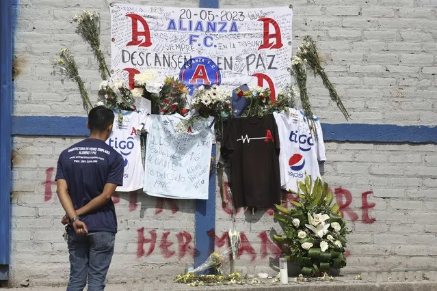 A fan of Alianza FC looks at a memorial set up as a tribute to the soccer fans killed in the recent Cuscatlan stadium stampede, outside the stadium in San Salvador, El Salvador, Monday, May 22, 2023. The tragedy occurred when stampeding fans pushed through one of the access gates during a quarterfinal Salvadoran league soccer match between Alianza and FAS. (Photo by Salvador Melendez/AP Photo)