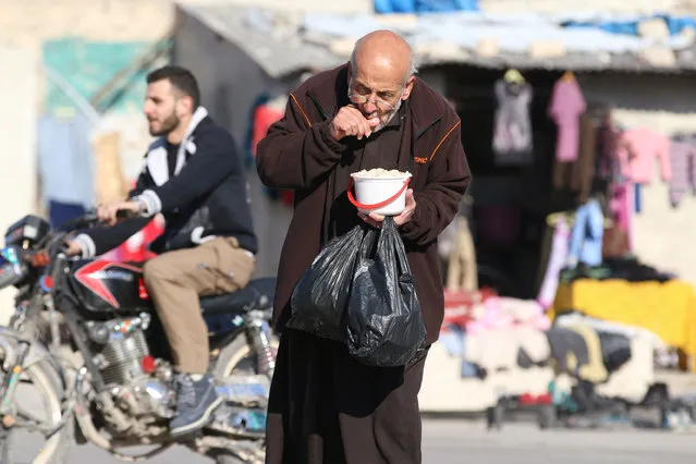 A man eats food that was distributed as aid in a rebel-held besieged area in Aleppo, Syria November 6, 2016. (Photo by Abdalrhman Ismail/Reuters)