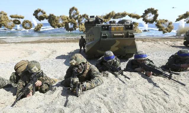 In this March 12, 2016, file photo, Marines of the U.S., left, and South Korea wearing blue headbands on their helmets, take positions after landing on a beach during the joint military combined amphibious exercise, called Ssangyong, part of the Key Resolve and Foal Eagle military exercises, in Pohang, South Korea. The Pentagon on Monday, June 18, 2018,  formally suspended a major military exercise planned for August with South Korea, a much-anticipated move stemming from President Donald Trump's nuclear summit with North Korean leader Kim Jong Un. (Photo by Kim Jun-bum/Yonhap via AP Photo)
