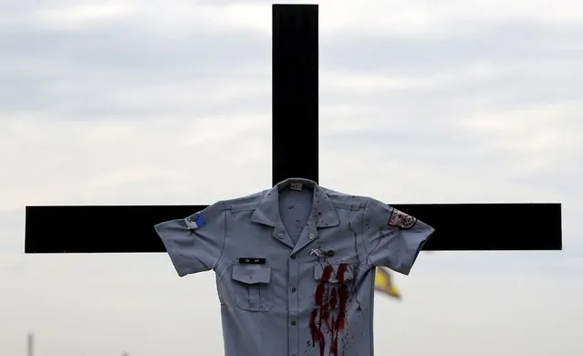 A police officer uniform placed by the NGO Rio de Paz (Peace Rio) is pictured on a cross on Copacabana beach, in memory of police officers killed in Rio de Janeiro, Brazil, December 10, 2015. Rio de Paz placed 61 pictures of police officers killed in confrontations with criminals in 2015 in Rio de Janeiro, according to the NGO. (Photo by Sergio Moraes/Reuters)