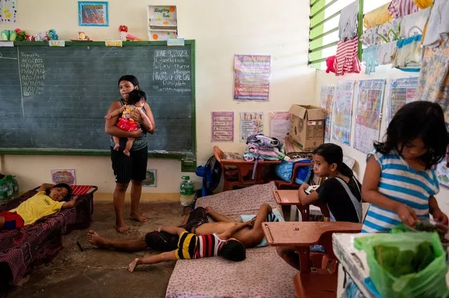 Elena Rosales, 23, holds her daughter inside a classroom converted into an evacuation site following the increased alert level of Mayon Volcano, in Daraga, Albay province, Philippines on June 11, 2023. (Photo by Lisa Marie David/Reuters)
