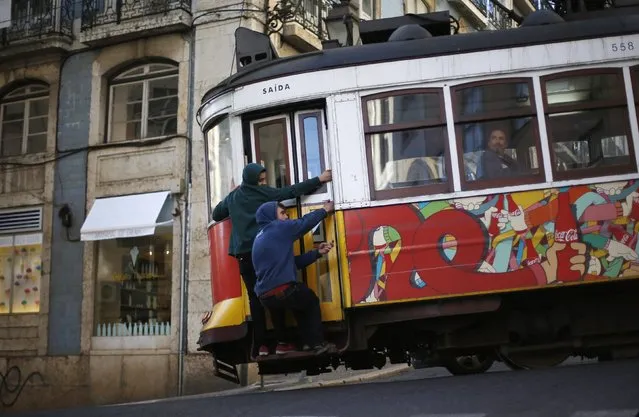 Two boys hold on to the side of a tram in downtown Lisbon January 26, 2015. (Photo by Rafael Marchante/Reuters)