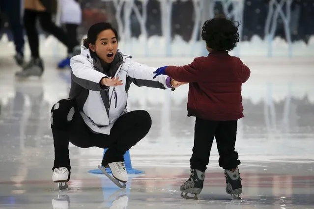 A woman encourages a child as they skate on skating rink at Bryant Park during unseasonably warm weather on Christmas Eve in the Manhattan borough of New York, December 24, 2015. (Photo by Carlo Allegri/Reuters)