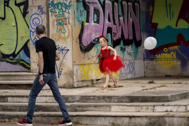 A little girl runs, backdropped by graffiti covered walls, in downtown Bucharest, Romania, Saturday, June 17, 2023. (Photo by Vadim Ghirda/AP Photo)