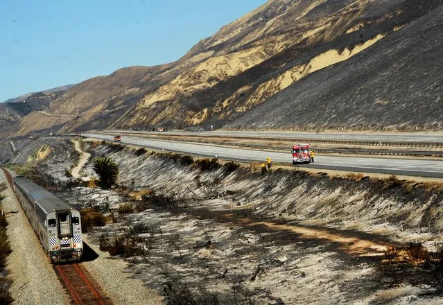 A train passes a burned area along Highway 101 in Ventura, Calif., Saturday, December 26, 2015. (Photo by Chuck Kirman/The Ventura County Star via AP Photo)