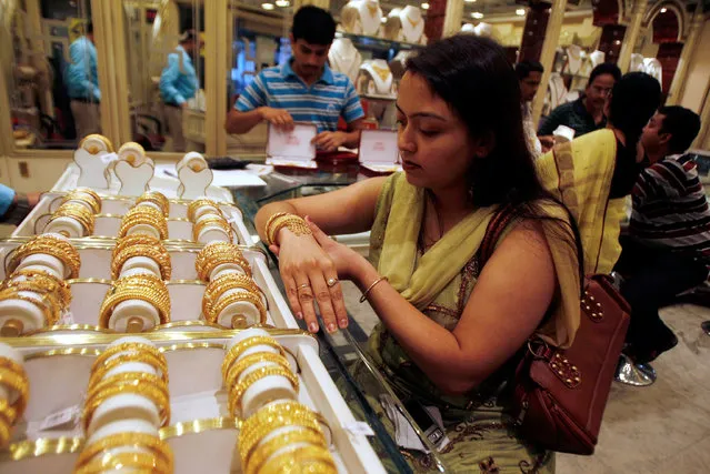 A woman tries on a gold bracelet at a jewellery showroom in the eastern Indian city of Siliguri November 4, 2009. (Photo by Rupak De Chowdhuri/Reuters)