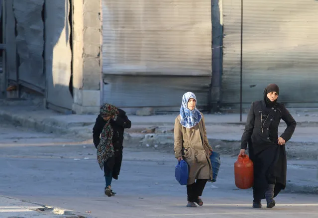 Civilians carry water containers as they walk along a street in the rebel-held besieged Tariq al-Bab neighborhood of Aleppo, Syria November 23, 2016. (Photo by Abdalrhman Ismail/Reuters)
