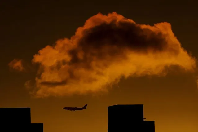 The shadow of a plane, left, is seen on a cloud as it prepares to land at Newark Liberty International Airport seen from The Heights neighborhood of Jersey City, N.J., Sunday, June 5, 2016. (Photo by Julio Cortez/AP Photo)
