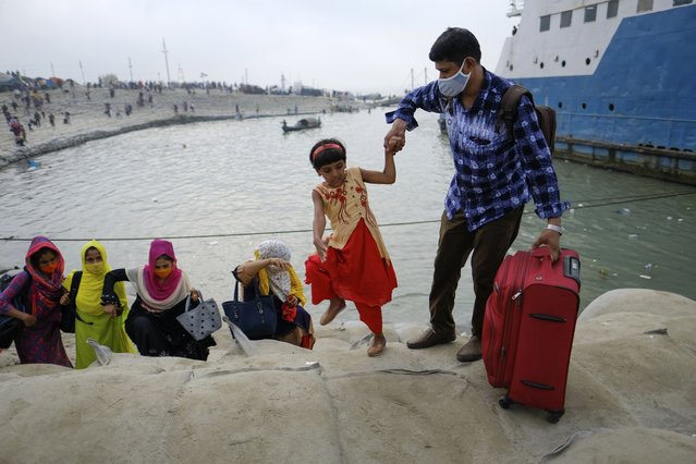 A man holds a child's hand as thousands of people leaving for their native places to celebrate Eid-al-Fitr rush to the Mawa ferry terminal ignoring risks of coronavirus infection in Munshiganj, Bangladesh, Thursday, May 13, 2021. (Photo by Mahmud Hossain Opu/AP Photo)