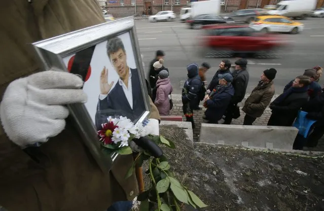 People stand in line to attend a memorial service before the funeral of Russian leading opposition figure Boris Nemtsov, as vehicles drive by, in Moscow, March 3, 2015. Several hundred Russians, many carrying red carnations, queued on Tuesday to pay their respects to Boris Nemtsov, the Kremlin critic whose murder last week showed the hazards of speaking out against Russian President Vladimir Putin. REUTERS/Maxim Shemetov 