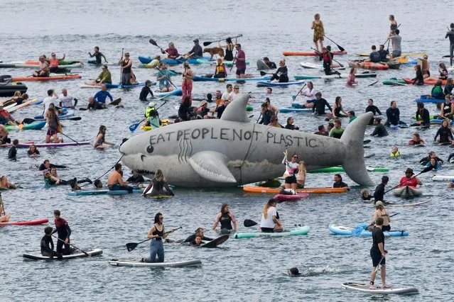 People ride kayaks and boards around a prop shark in a protest in Gyllyngvase beach, Falmouth, during the G7 summit in Cornwall, Britain, June 12, 2021. (Photo by Toby Melville/Reuters)