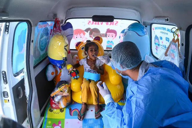 A medical worker takes swab sample from a girl to test for the Covid-19 coronavirus inside a van with inflatable and soft toys launched by Delhi Police in association with Star Imaging and Path lab, in New Delhi on July 1, 2021. (Photo by Prakash Singh/AFP Photo)
